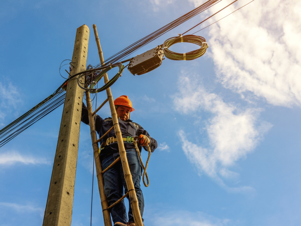 Técnico de concessionária trabalhando na rede elétrica para restabelecer o fornecimento de energia dentro do prazo determinado pela ANEEL.